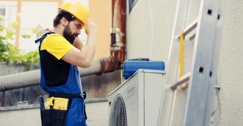 Electrician checking air conditioner Skilled electrician contracted to check up on outdoor air conditioner starting work shift. Trained worker wearing protective gear preparing to service faulty external hvac system